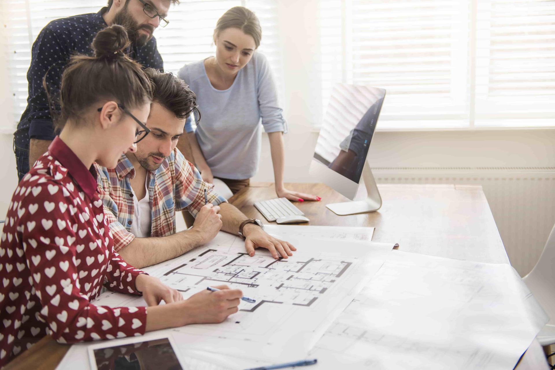 coworkers-at-office-with-architecture-plans-and-a-computer-min